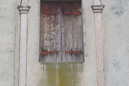 Finestra in legno rovinato sotto ad un arco antico