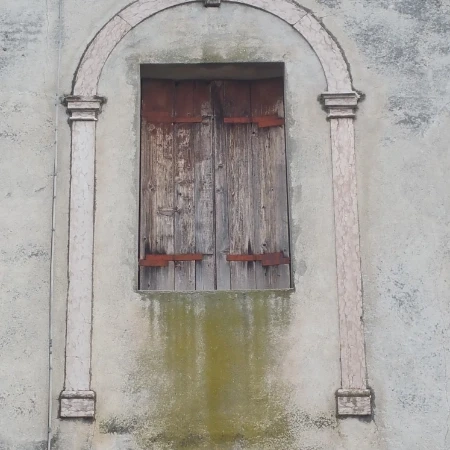 Finestra in legno rovinato sotto ad un arco antico