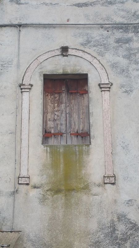 Finestra in legno rovinato sotto ad un arco antico